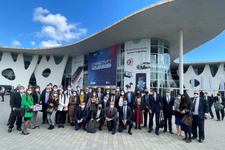 Group of professionals attending a conference at a modern building with banners and clear blue sky.